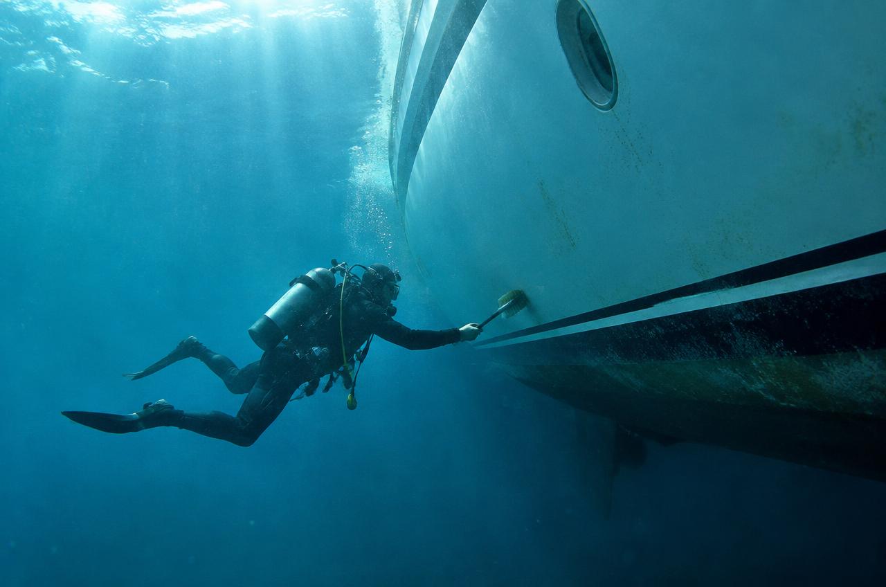Diver cleaning the hull of a luxury yacht underwater